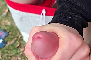 Husband fingers wife's shaved pussy outdoors with reach around.