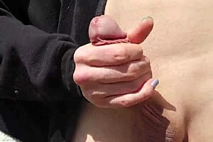 Husband fingers wife's shaved pussy outdoors with reach around.