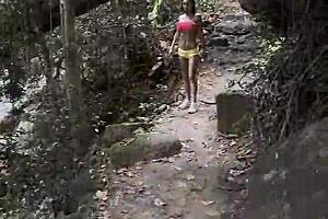 Monika Fox in pink top and yellow shorts, walking through jungle and waterfalls, feeling free.