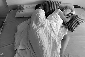 A quiet amateur couple shares an intimate spooning moment in bed late at night