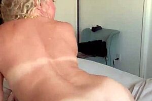 Sexy blonde cougar milf strips lingerie, spreads curvy pussy wide on bed.