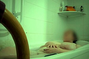 Mature white woman teases her boobs while bathing in oil